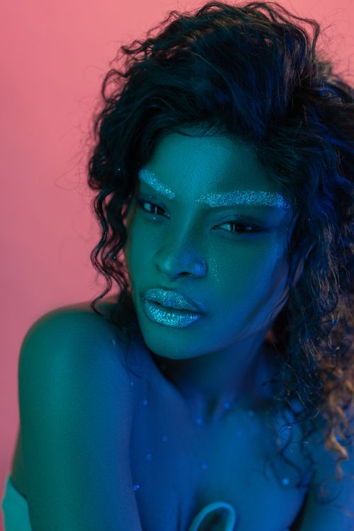Free Striking portrait of a woman with glitter makeup, set against a vivid two-tone background. Stock Photo