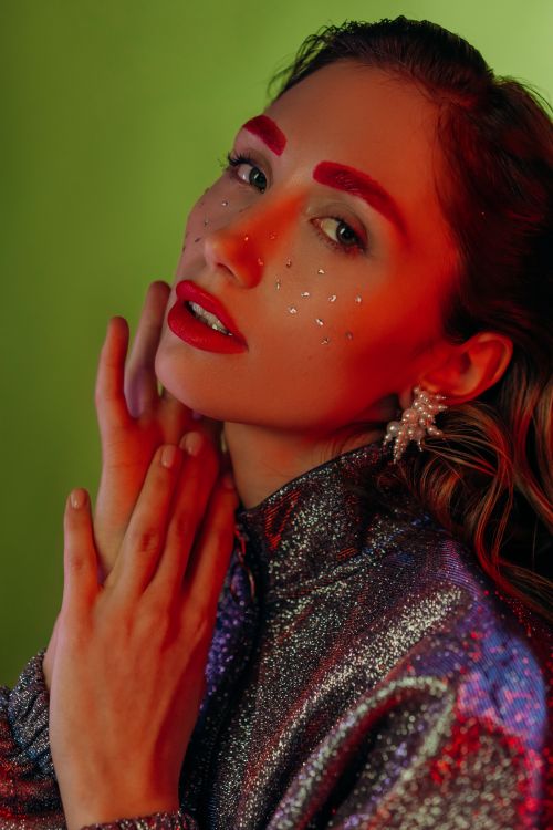 Free Close-up portrait of a stylish woman with artistic makeup and glitter accents on a bright background. Stock Photo