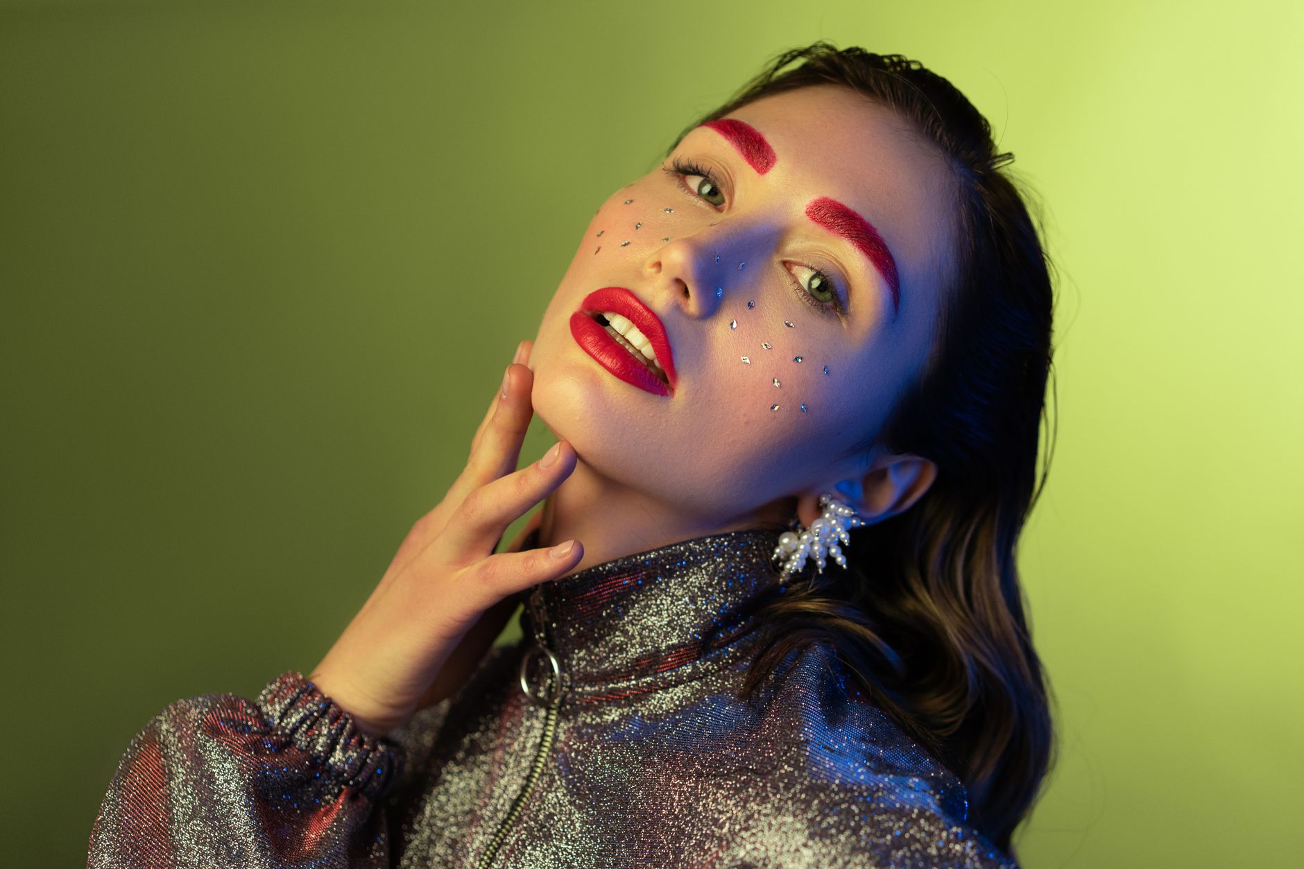 Striking portrait of woman with bold makeup, glitter, and a metallic jacket.
