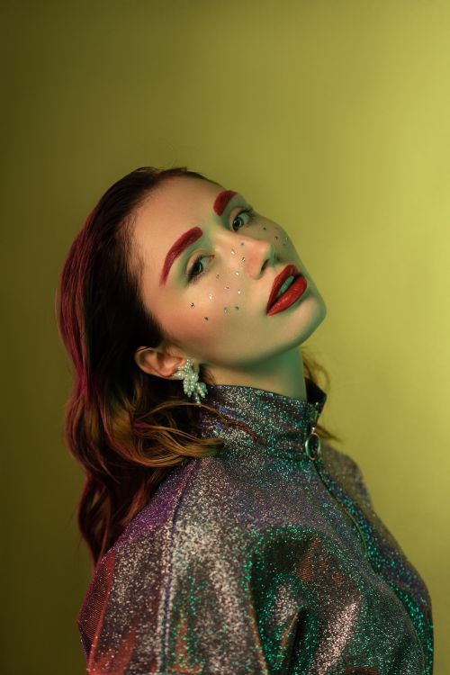 Free Elegant woman in glitter jacket and makeup posing on an olive background. Stock Photo