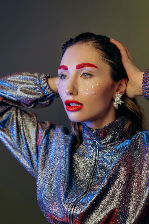 Free Close-up portrait of a woman with bold makeup, glitter, and a shiny outfit. Stock Photo
