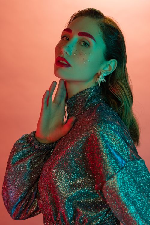 Free Vibrant studio portrait of a woman with bold makeup and glitter outfit. Stock Photo