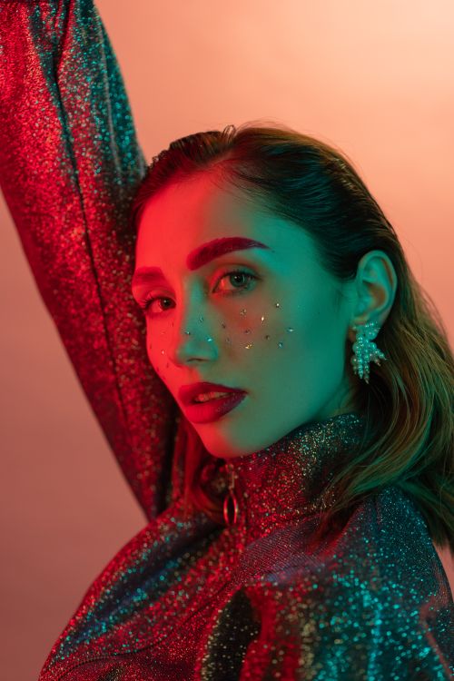 Free Stunning portrait of a fashionable woman with glitter makeup in vibrant lighting. Stock Photo