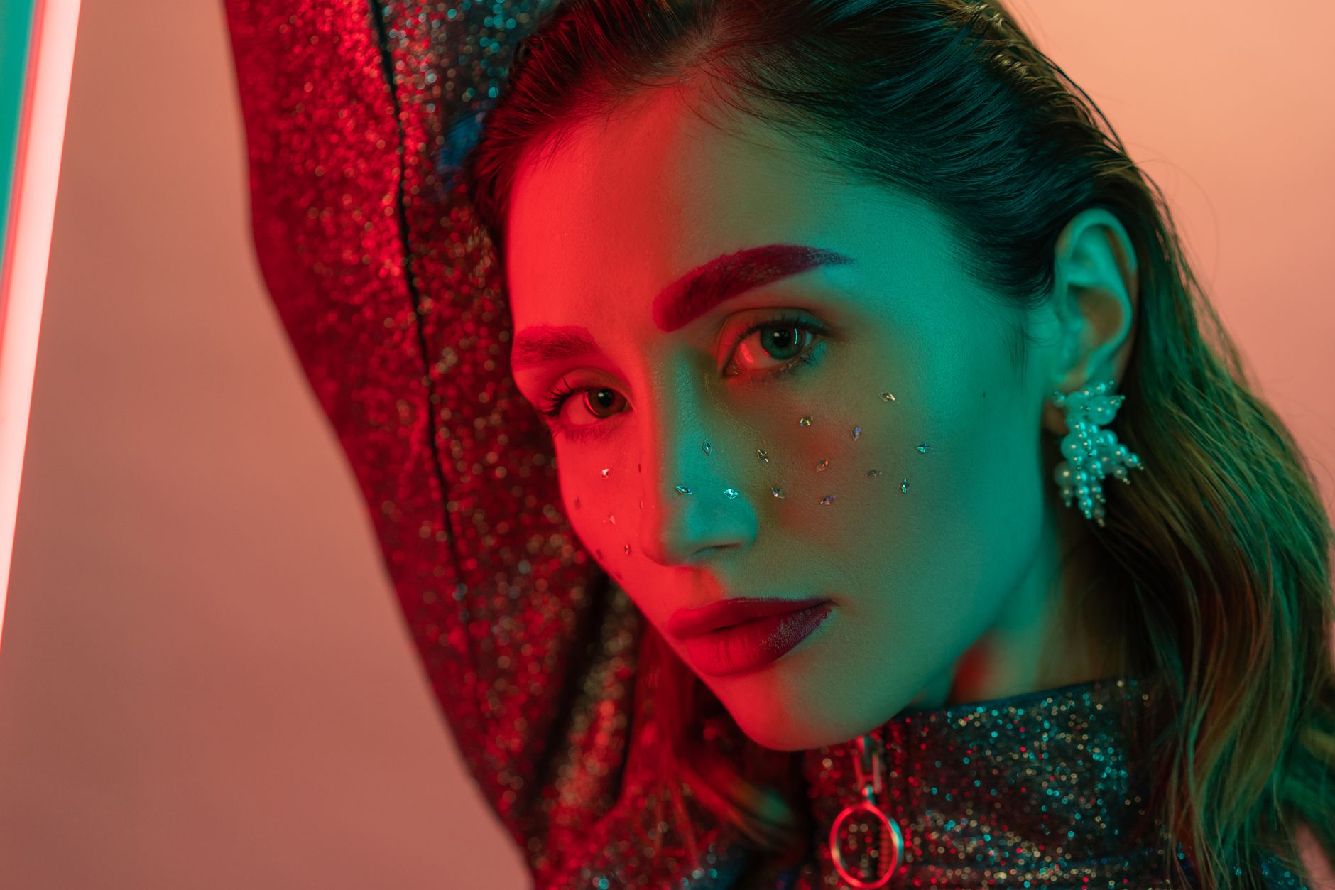 Striking portrait of a woman with glittery makeup and bold lighting.