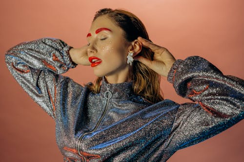 Stylish woman in a glittering outfit with bold makeup, exuding glamour and elegance.