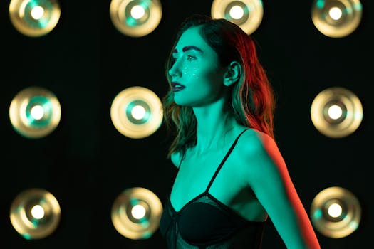 A woman in a studio with colorful lights and creative makeup, posing sideways.