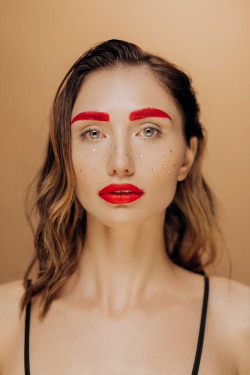 Free Stylish portrait of a woman with bold red makeup and creative sparkle design. Stock Photo