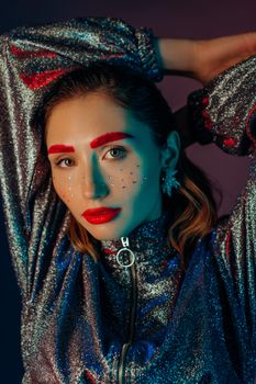 A fashionable young woman with vibrant makeup and glittering outfit.
