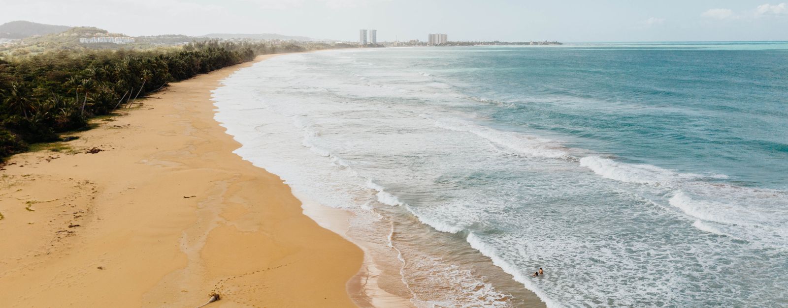 Golden sand beach in Puerto Rico with gentle waves, ideal for a tropical summer vacation.