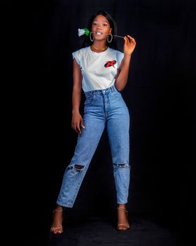 Stylish African woman posing confidently in a studio setting wearing a white shirt and jeans.