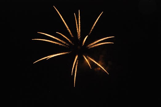 Golden fireworks burst against a dark night sky, perfect for celebrations or events.