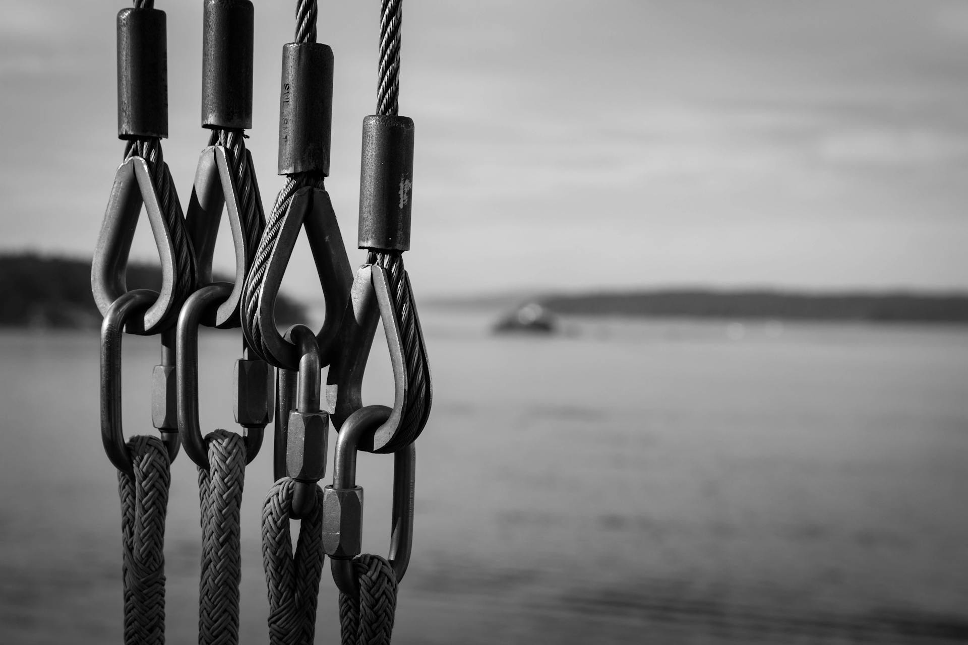 Close-up of nautical cables overlooking the sea in black and white.