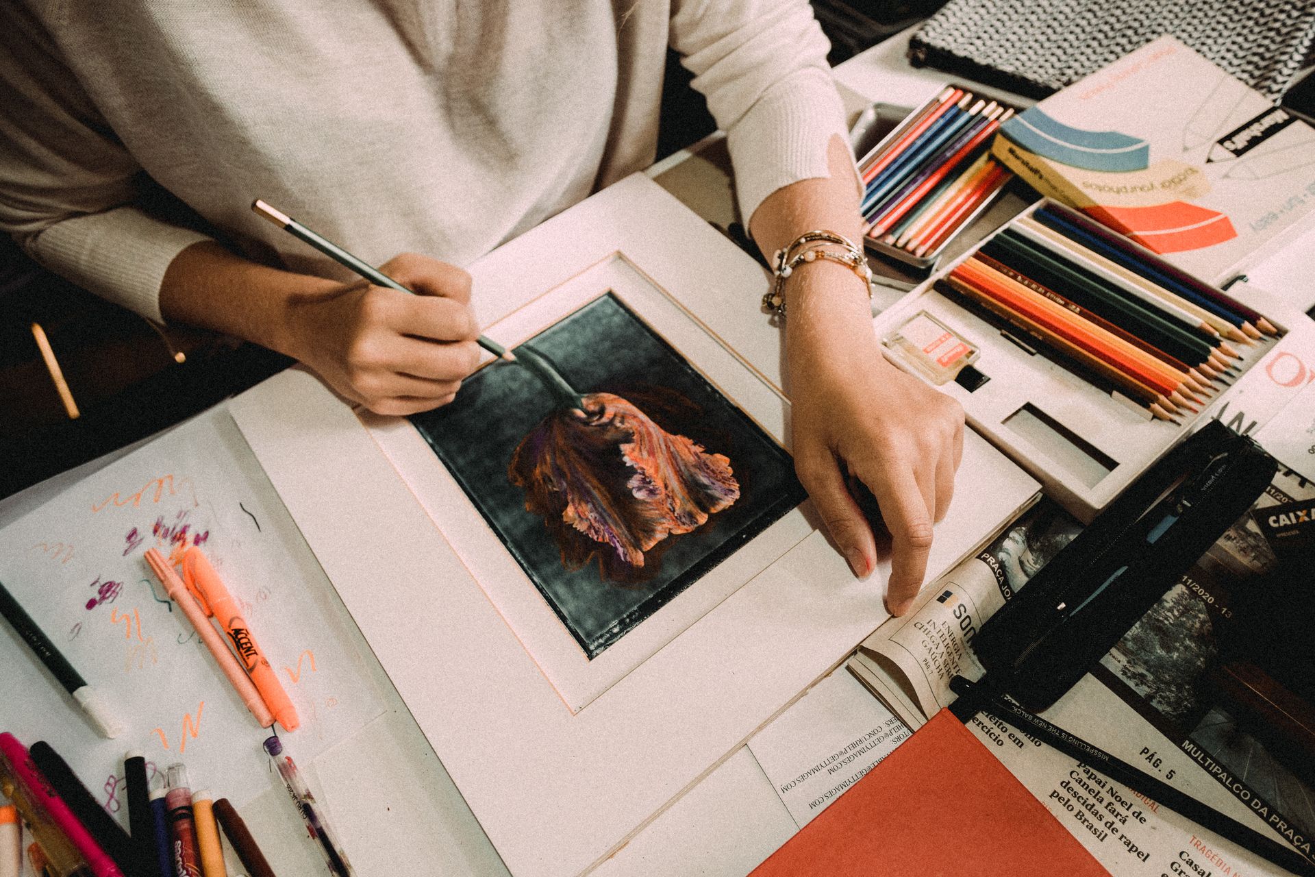 Artist working on a colorful drawing in a creative workspace with pencils and paper.
