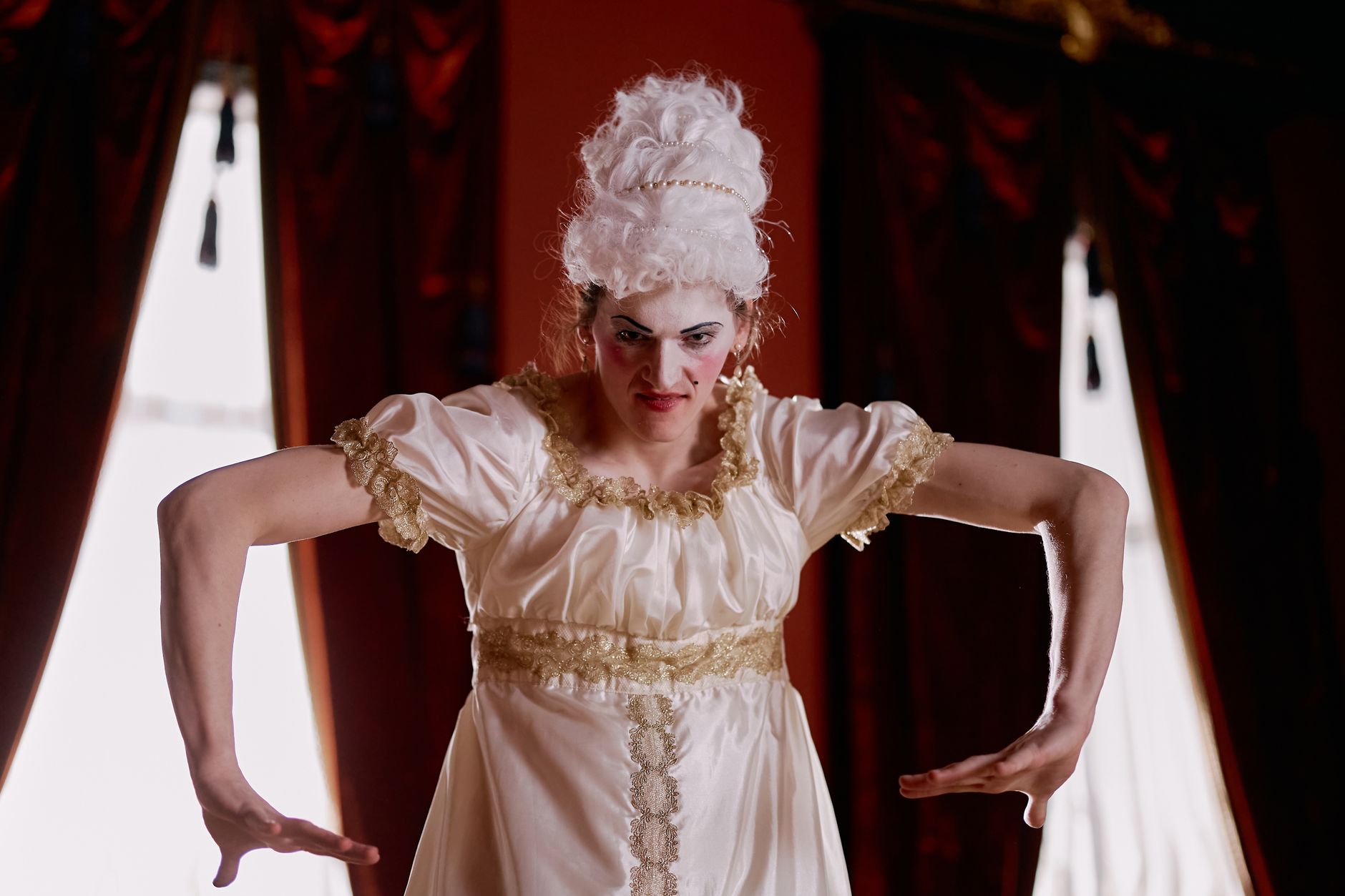 Elegant portrait of a performer in Victorian costume with theatrical pose indoors.