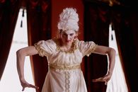 Elegant portrait of a performer in Victorian costume with theatrical pose indoors.