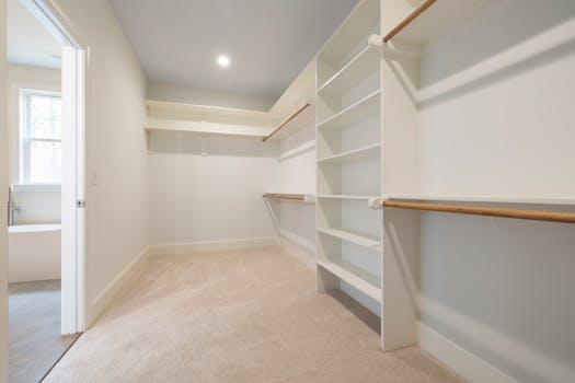 A bright and spacious empty walk-in closet with white shelving and hanging rods, ideal for organizing.