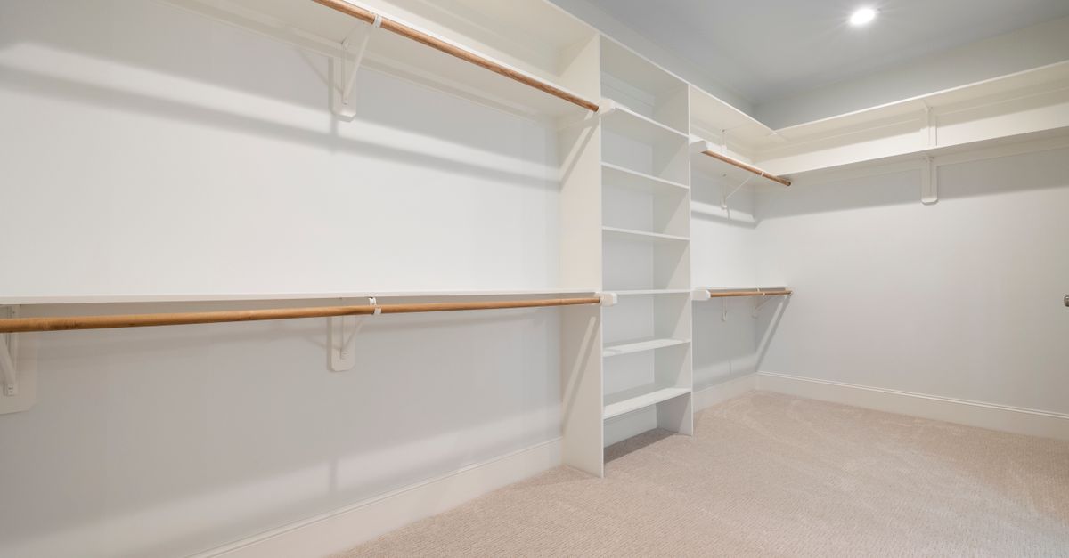 Modern empty walk-in closet with ample shelves and hanging rods for storage.