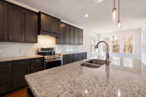 Free Spacious kitchen with granite island, dark wood cabinets, and large windows. Stock Photo