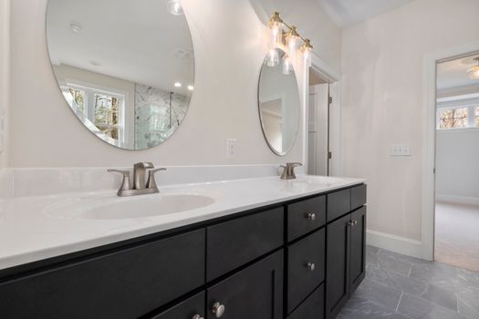 Elegant bathroom interior featuring round mirrors and contemporary vanity.