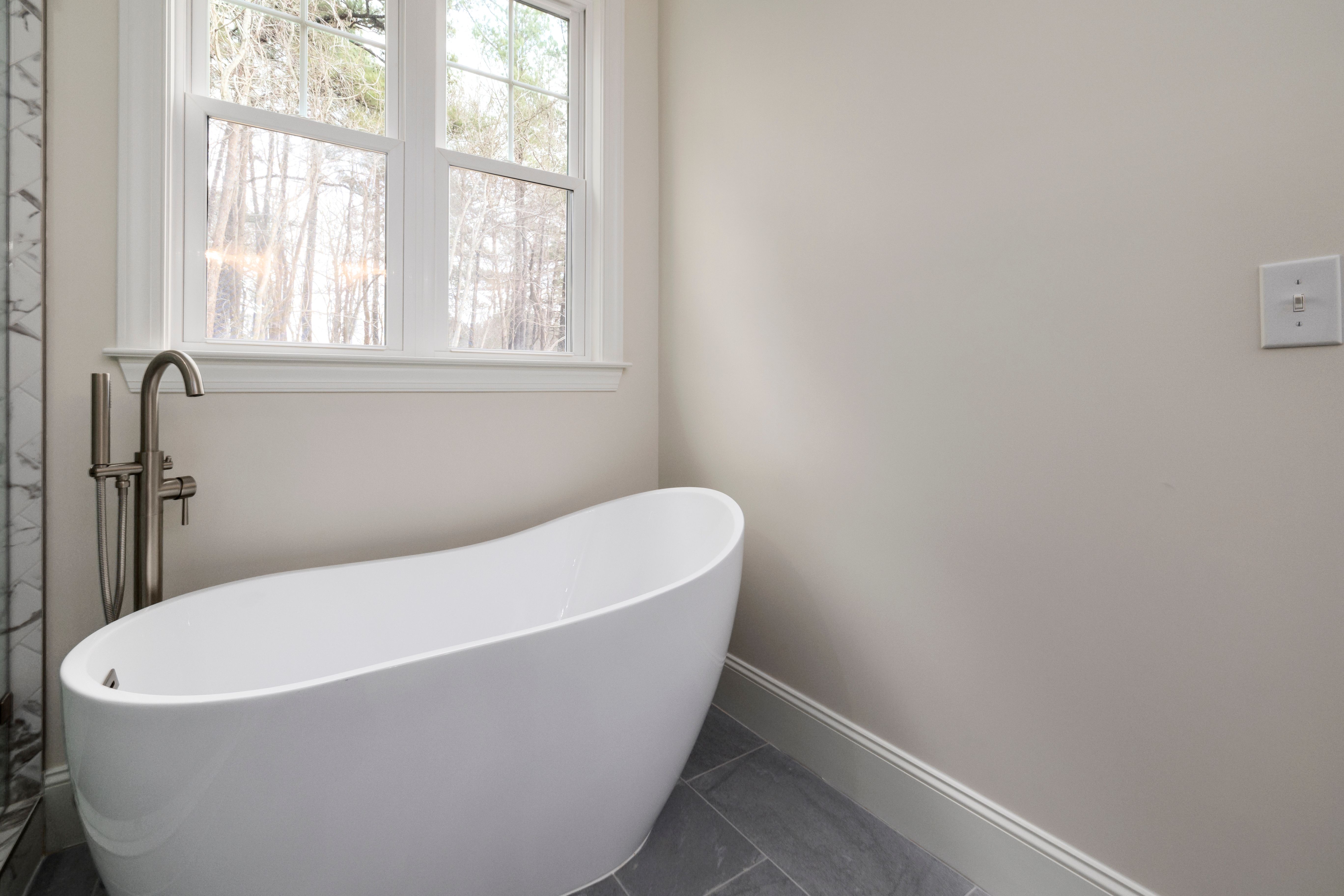 Floor-mounted tub filler installation next to a freestanding pedestal tub