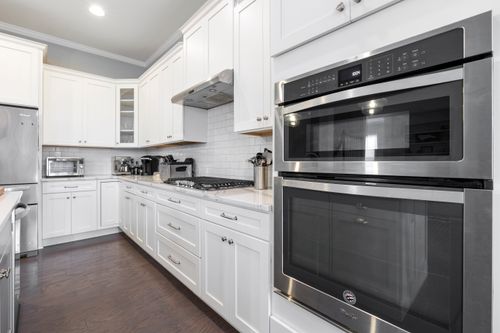 Free Sleek and modern white kitchen featuring stainless steel appliances and elegant cabinetry. Stock Photo