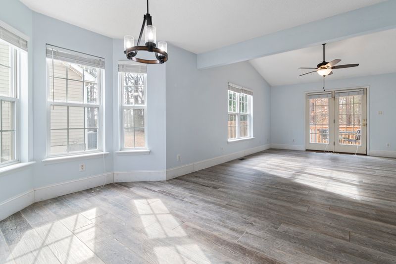 Bright empty living room with wooden floor and ceiling fan, ideal for interior design use.