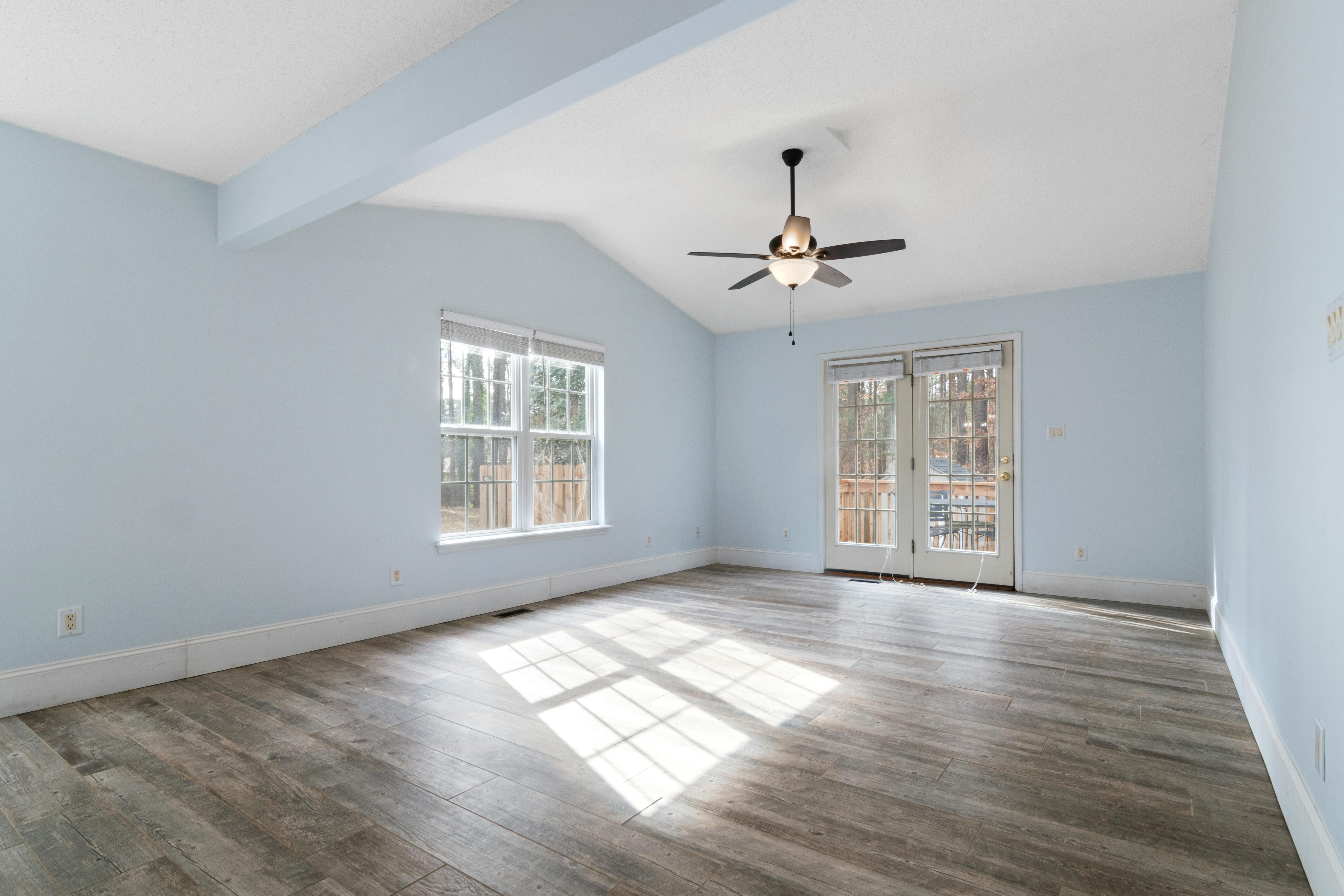Nick's Electrical LLC - Modern empty room with blue walls and ceiling fan, ideal for interior design inspiration.