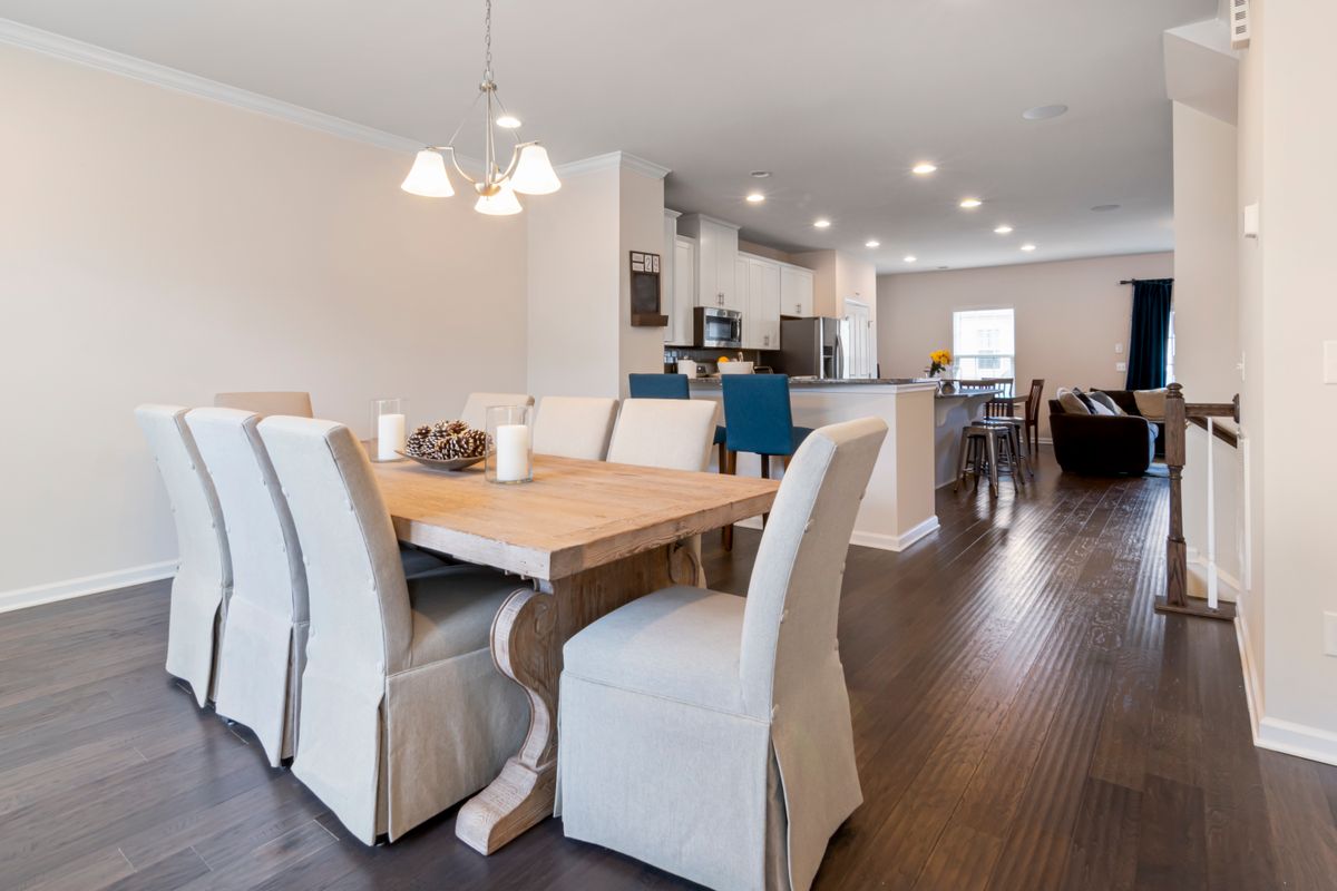 Modern dining room with wooden table, upholstered chairs, lighting and wall decor