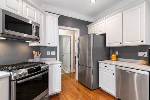 Silver Refrigerator Beside White Wooden Kitchen Cabinets