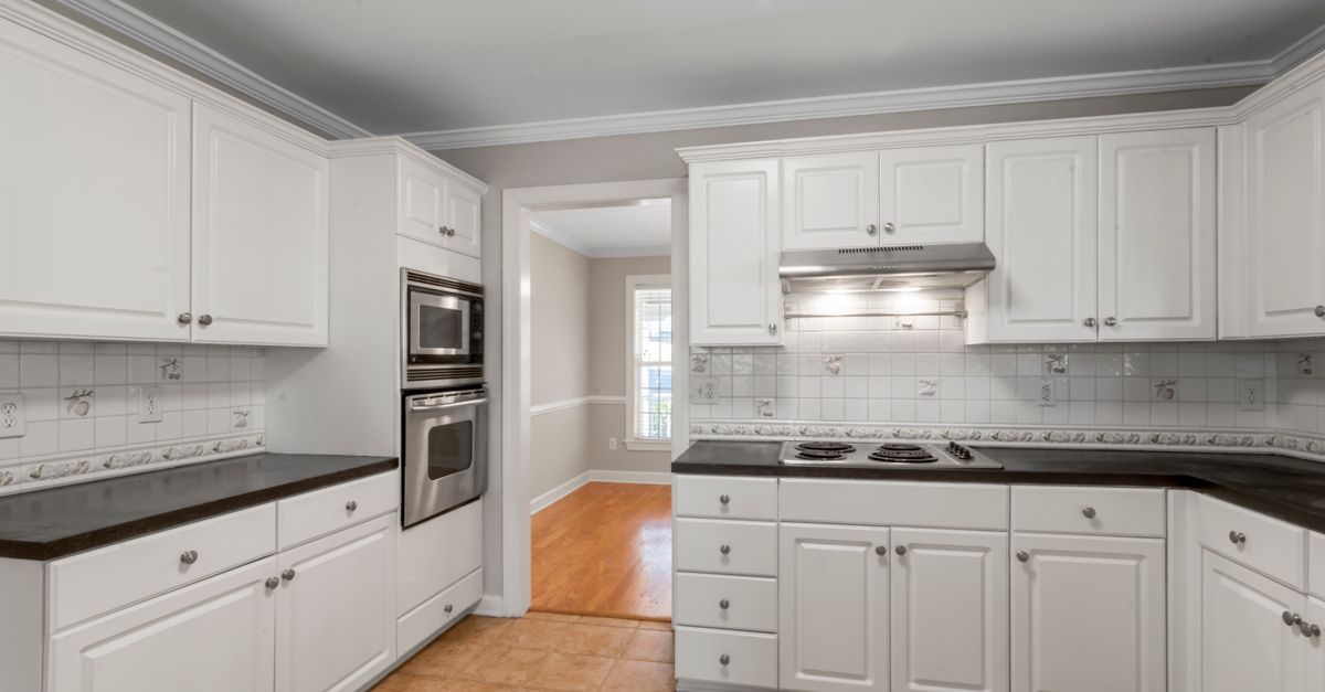 Spacious white kitchen featuring stainless steel appliances and dark countertops.