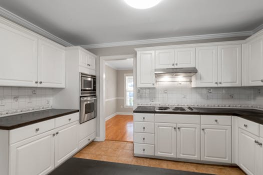 Spacious white kitchen featuring stainless steel appliances and dark countertops.