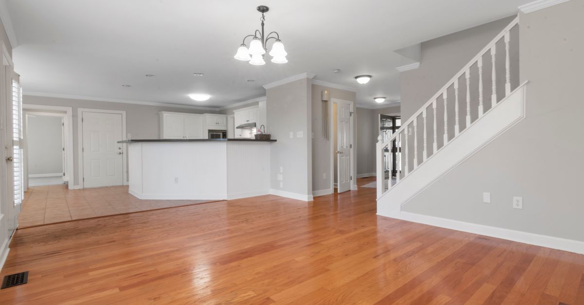 Bright and airy open floor plan with hardwood flooring and white kitchen cabinets.