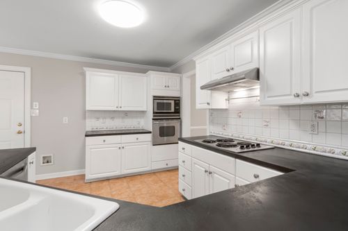 Free A clean and modern kitchen featuring white cabinets and black countertops with elegant lighting. Stock Photo