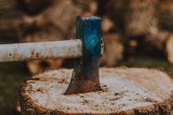 Ax with weathered handle and blade in cut tree trunk with dry surface in countryside