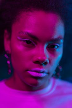 A close-up vibrant portrait of a stylish woman with bold makeup and colorful lighting.