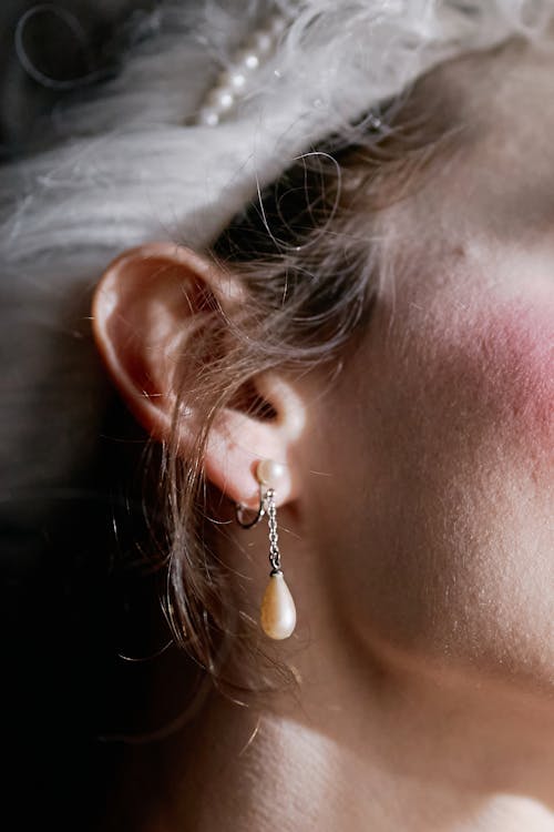 Close-up of a Person Wearing a Dangling Pearl Earring