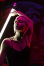 Woman in Black Spaghetti Strap Top with Hoop Earrings Holding an Illuminated Fluorescent Lamp