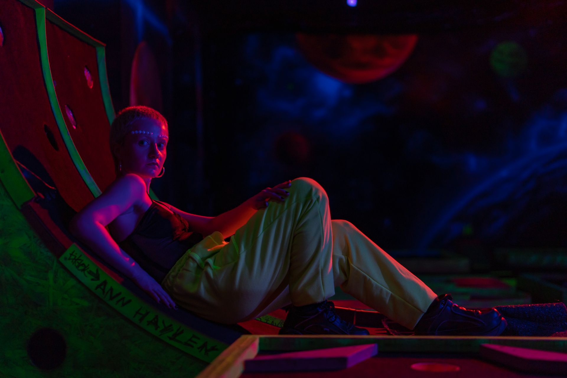 Creative fashion photoshoot with neon lighting and futuristic makeup. Ultraviolet colors enhance the artistic ambiance.