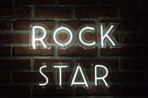 Bright neon sign reading 'Rock Star' against a dark brick wall, evoking a modern and urban vibe.