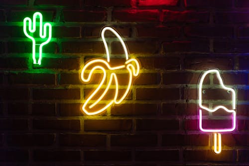 Close-Up Shot of Neon Light Signages on a Brick Wall