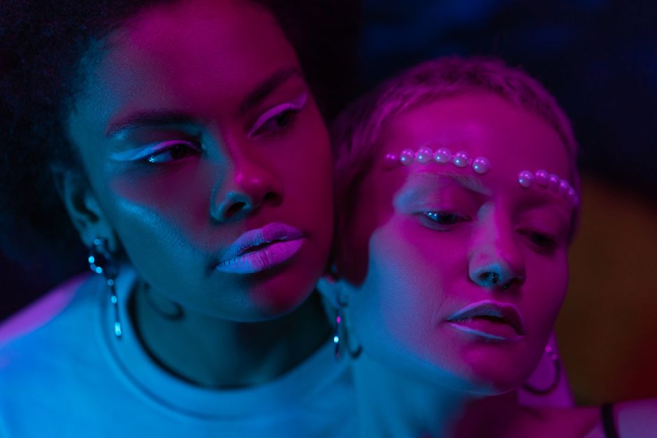 Artistic close-up of two women in neon lighting, highlighting modern fashion and expression.