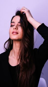 Portrait of a young woman with eyes closed, hand on head, exuding confidence and style.