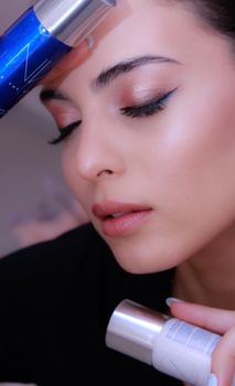 Close-up portrait of a woman with makeup, holding skincare products, exuding elegance and beauty.