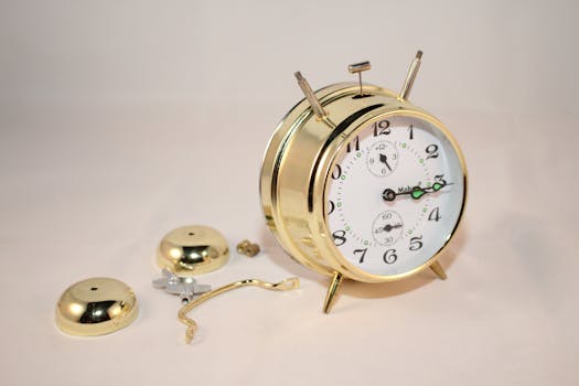 Close-up of a gold analogue alarm clock showing disassembled parts and intricate detail.