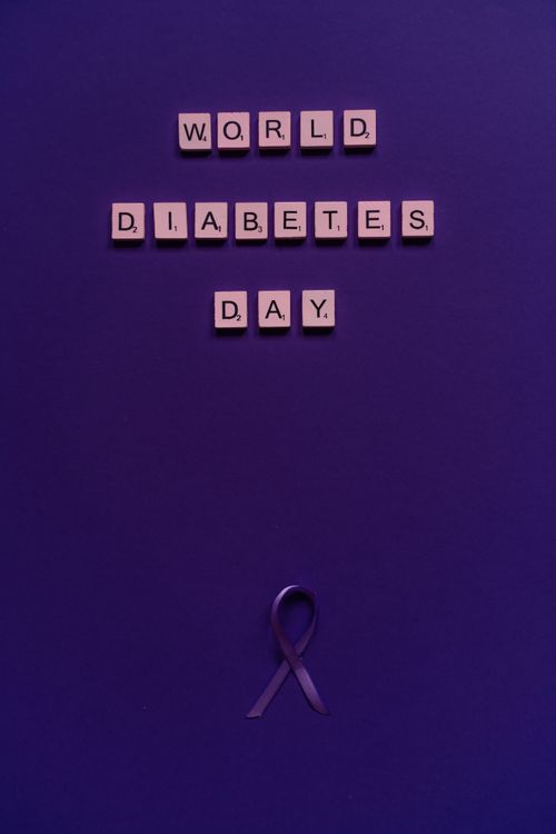 Free Purple background with 'World Diabetes Day' in scrabble tiles and ribbon. Stock Photo