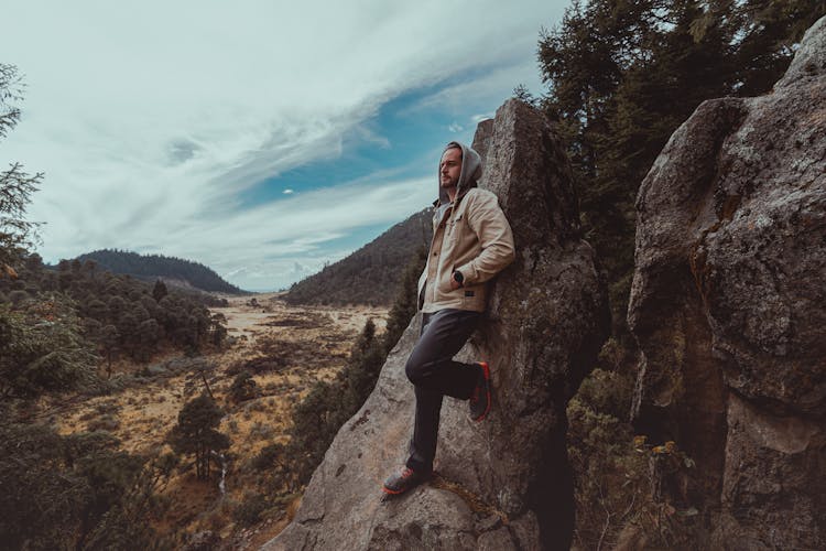 A Man In Hoodie Jacket Leaning On A Rock Formation