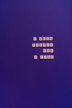 Scrabble tiles on a purple background spell out 'I wear purple for a cure', symbolizing support.