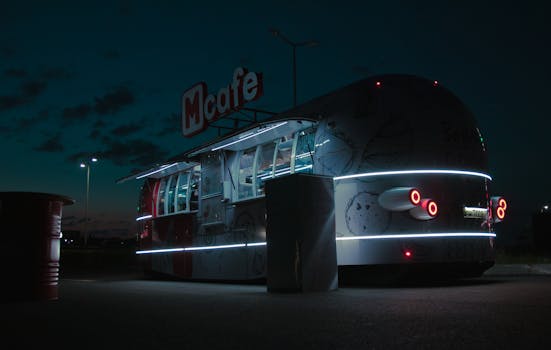 Illuminated McCafe food truck parked at night, offering street food services in an urban environment.
