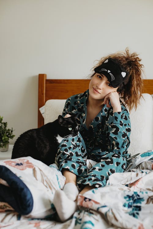Young woman in sleepwear with cat on bed