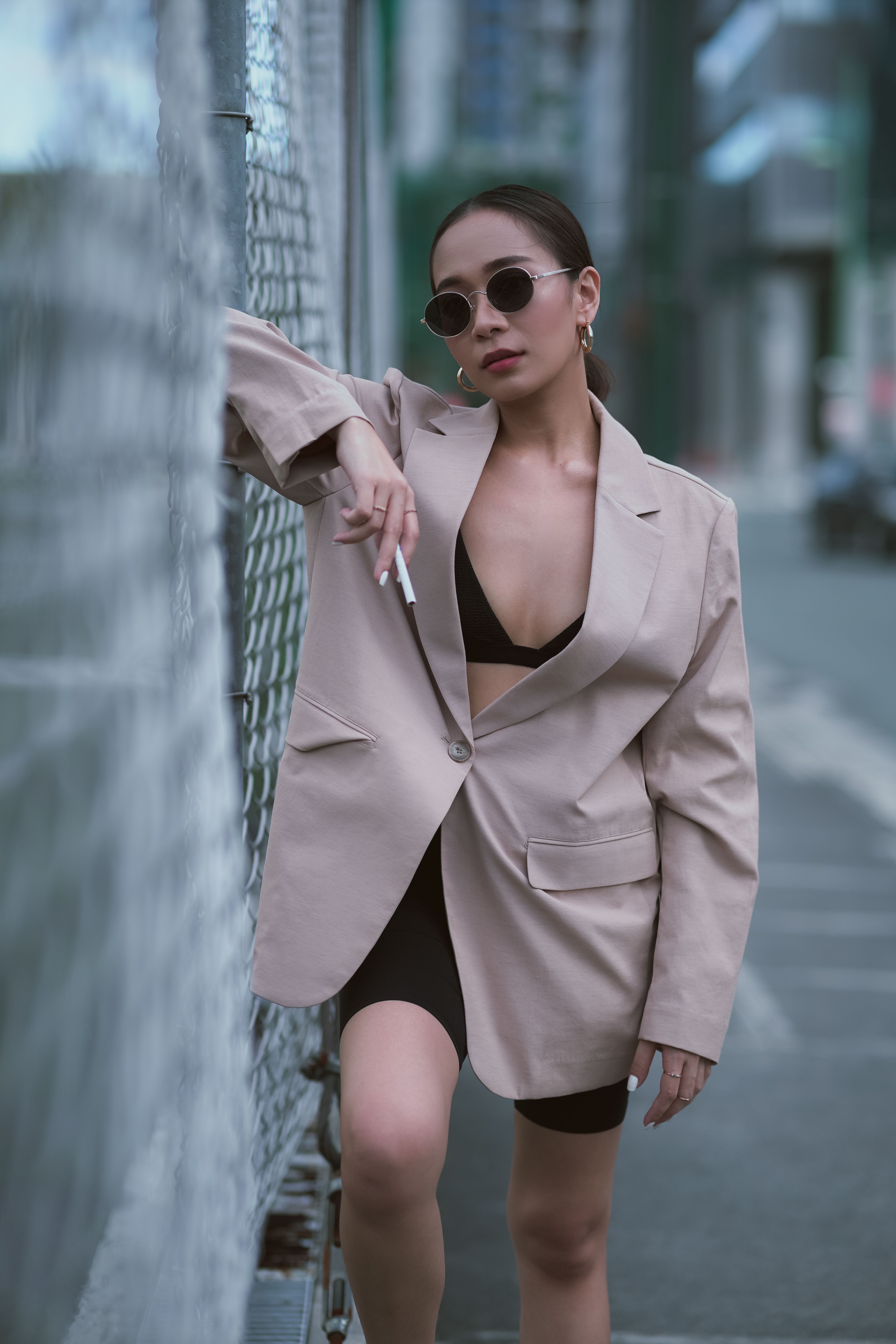 Trendy woman in oversized blazer and sunglasses poses confidently outdoors.